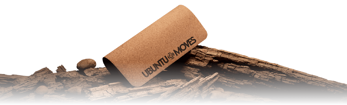 The Ubuntu Moves cork mat, rolled and resting on driftwood